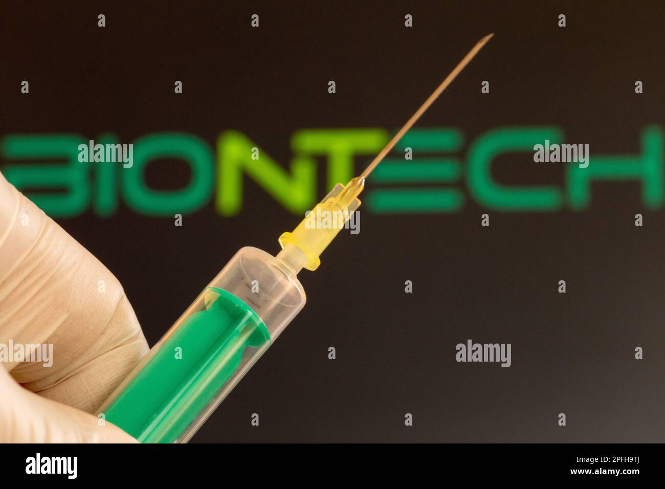 Immagine simbolo vaccinazione a corona/Biontech: Primo piano di un ago ipodermico, logo Biontech sullo sfondo. Il dibattito sul possibile danno da vaccino i Foto Stock