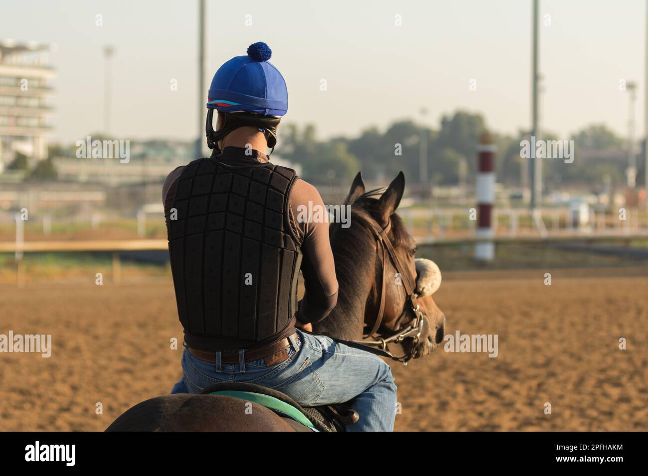 Un pilota di esercitazione nell'industria di corsa del cavallo, siede montato sul suo cavallo che guarda altri corridori nell'allenamento mattutino. Foto Stock
