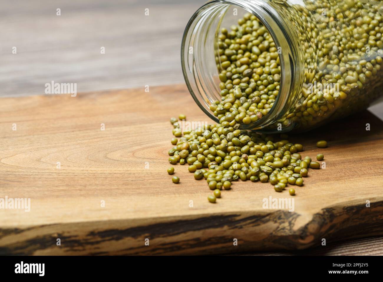 Fagiolini verdi che escono da un vaso di vetro su uno sfondo di legno. Micro verde e vegan concetto di cibo sano. Foto Stock