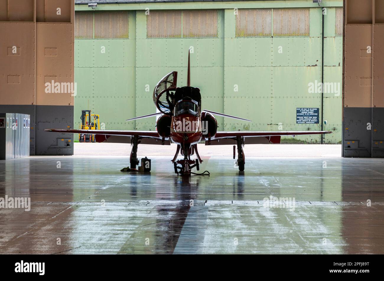 Royal Air Force Red Arrows mostra il team BAe Hawk T1 jet plane in un hangar al RAF Scampton, Lincolnshire, UK. Incorniciato da porte hangar Foto Stock