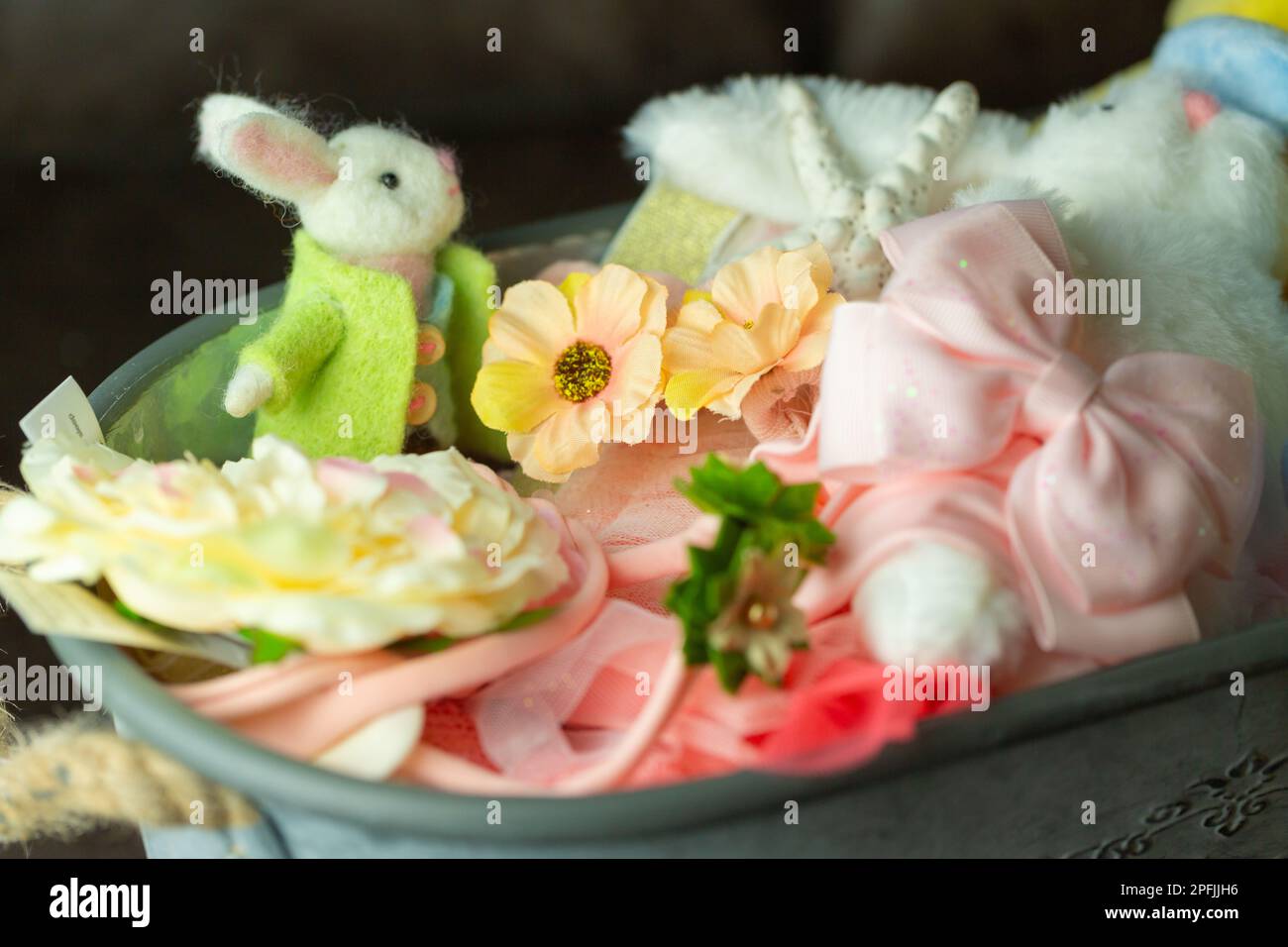 Primo piano di un coniglietto pasquale in feltro e vestiti e oggetti colorati in un contenitore. Foto Stock