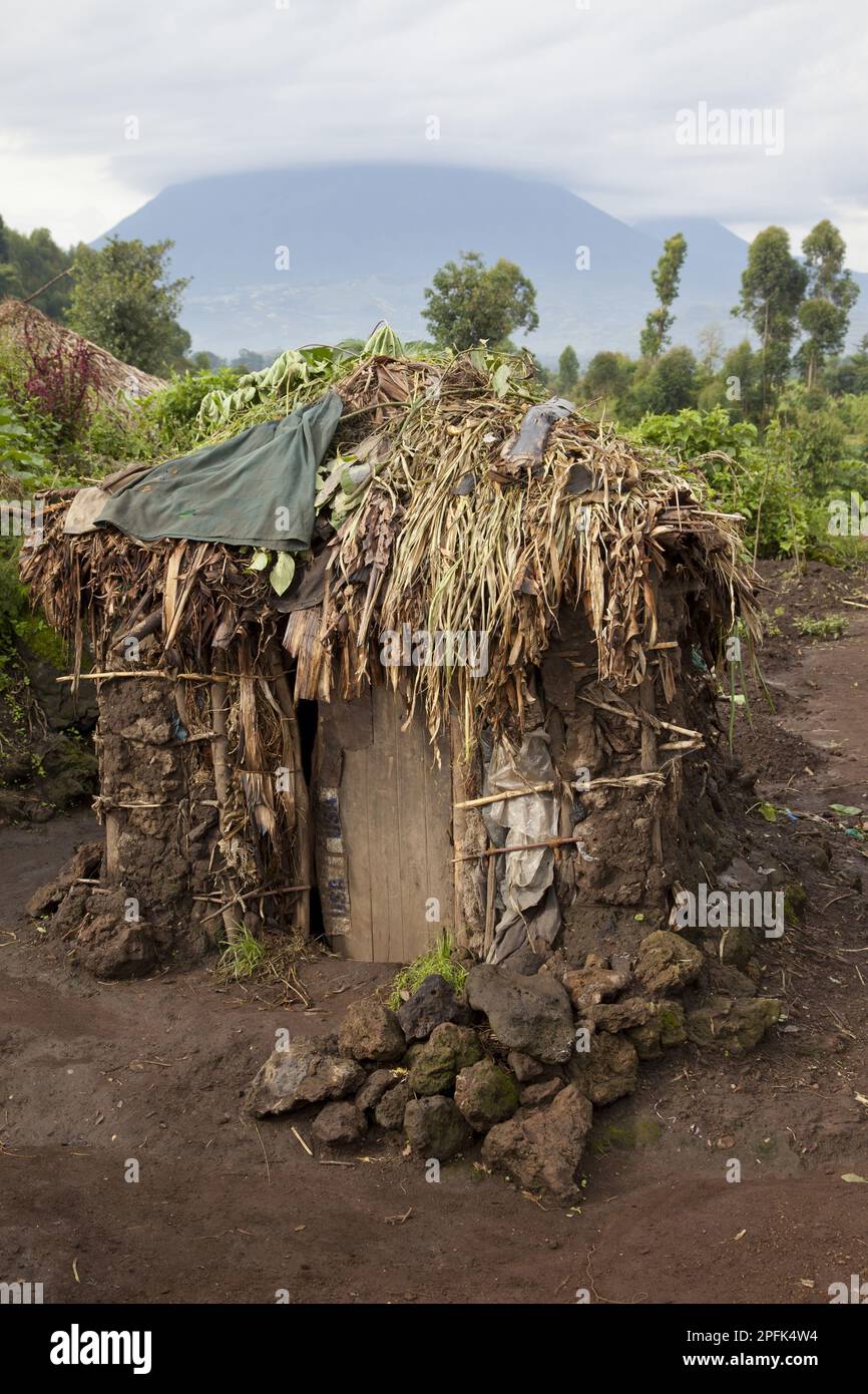 Rifugio di fango nel villaggio di Pygmy, con il vulcano sullo sfondo, le montagne di Virunga, Uganda Foto Stock