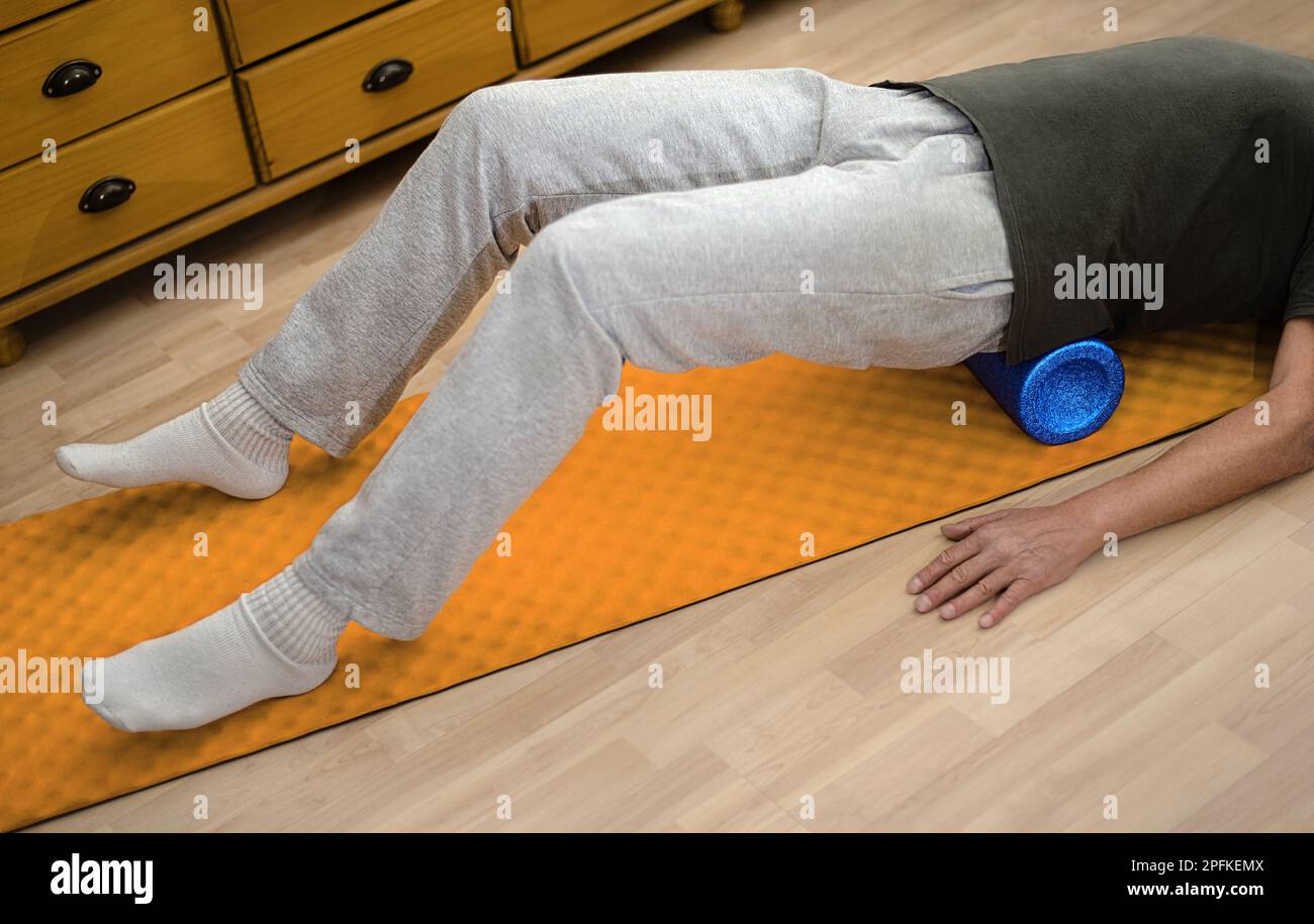 Uomo con fascia roll esercizio sul pavimento per la schiena muscolatura rulli massaggio stretching laminazione Foto Stock