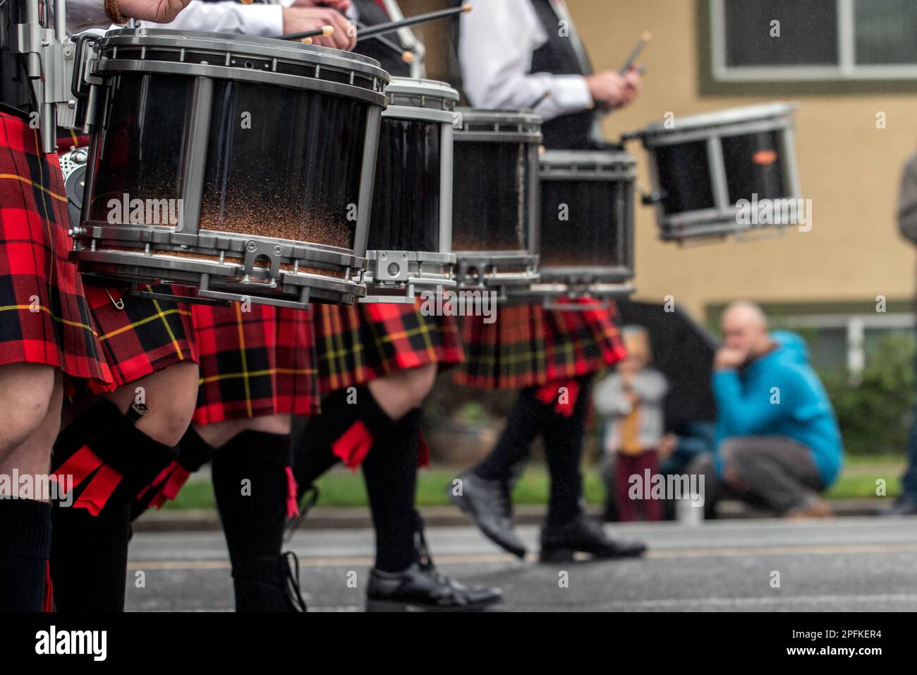 Banda scozzese di marcia con batteria che indossa i tradizionali kilt e la manichetta dei kilt, mantenendo la cadenza dei ritmi durante la sfilata. Foto Stock