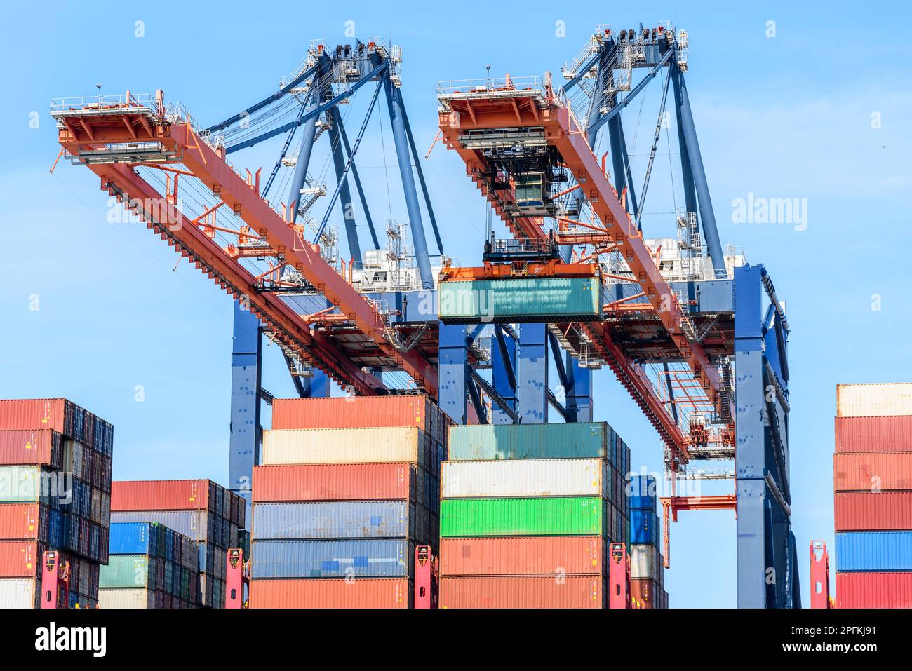 Enormi gru portuali che caricano una nave da carico con container in una giornata estiva di sole Foto Stock