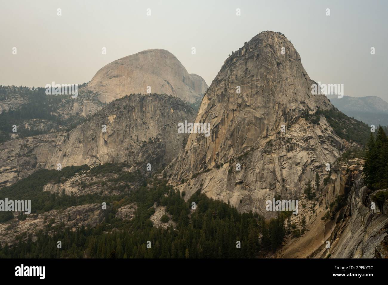 Berretto Liberty con il Monte Broderick e mezzo Duomo in lontananza in una giornata fumosa a Yosemite Foto Stock