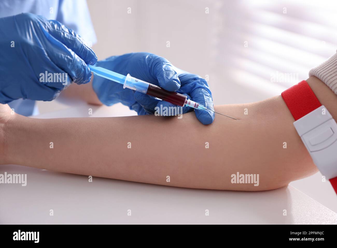 Medico che preleva un campione di sangue di paziente con siringa in ospedale, primo piano Foto Stock