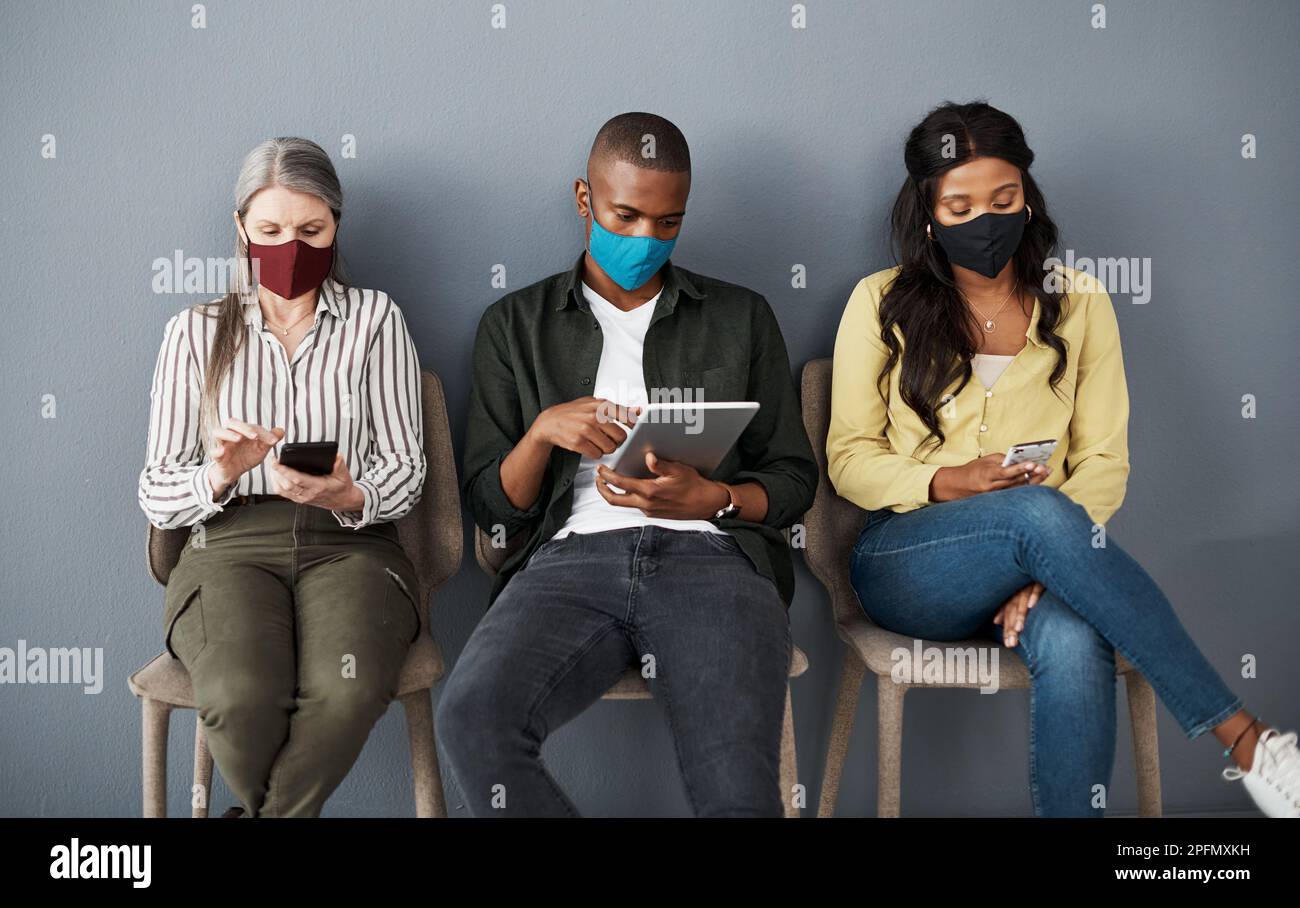 Razionato i miei respiri, ha detto che Id preso troppi oggi. un gruppo cauto di persone che si allontanano socialmente mentre utilizzano i loro dispositivi smart contro un grigio Foto Stock
