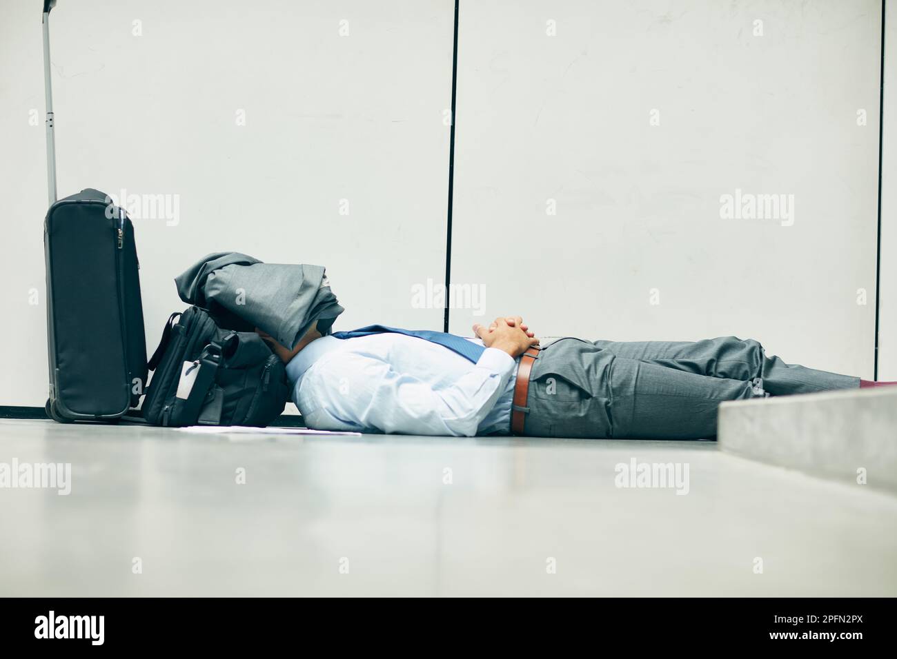 SSH, non sapranno im prendere un pisolino. un uomo d'affari irriconoscibile che dorme in un terminal aeroportuale e che gli copra il volto con la giacca. Foto Stock