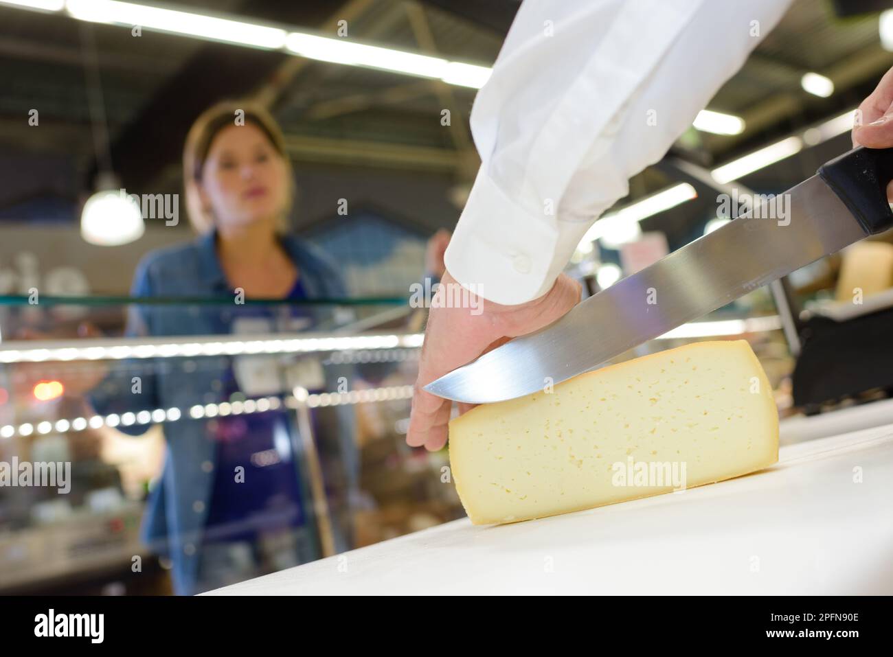 Il formaggio viene affettato per il cliente Foto Stock