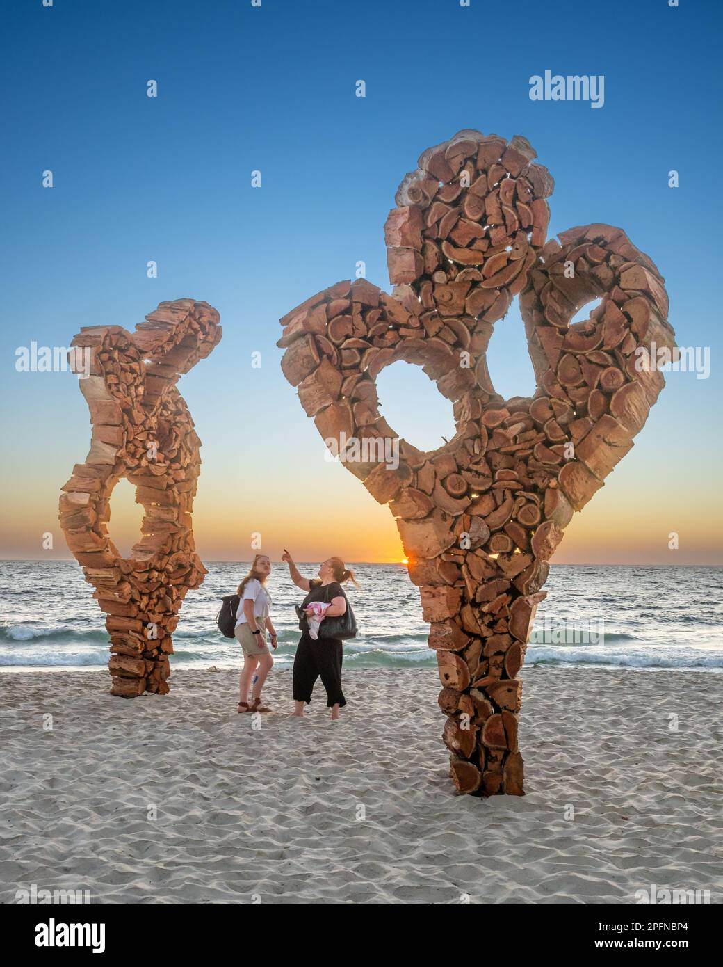 Due donne non identificate che ispezionano un'opera d'arte durante le sculture del mare a Cottesloe Beach a Perth, Australia Occidentale Foto Stock