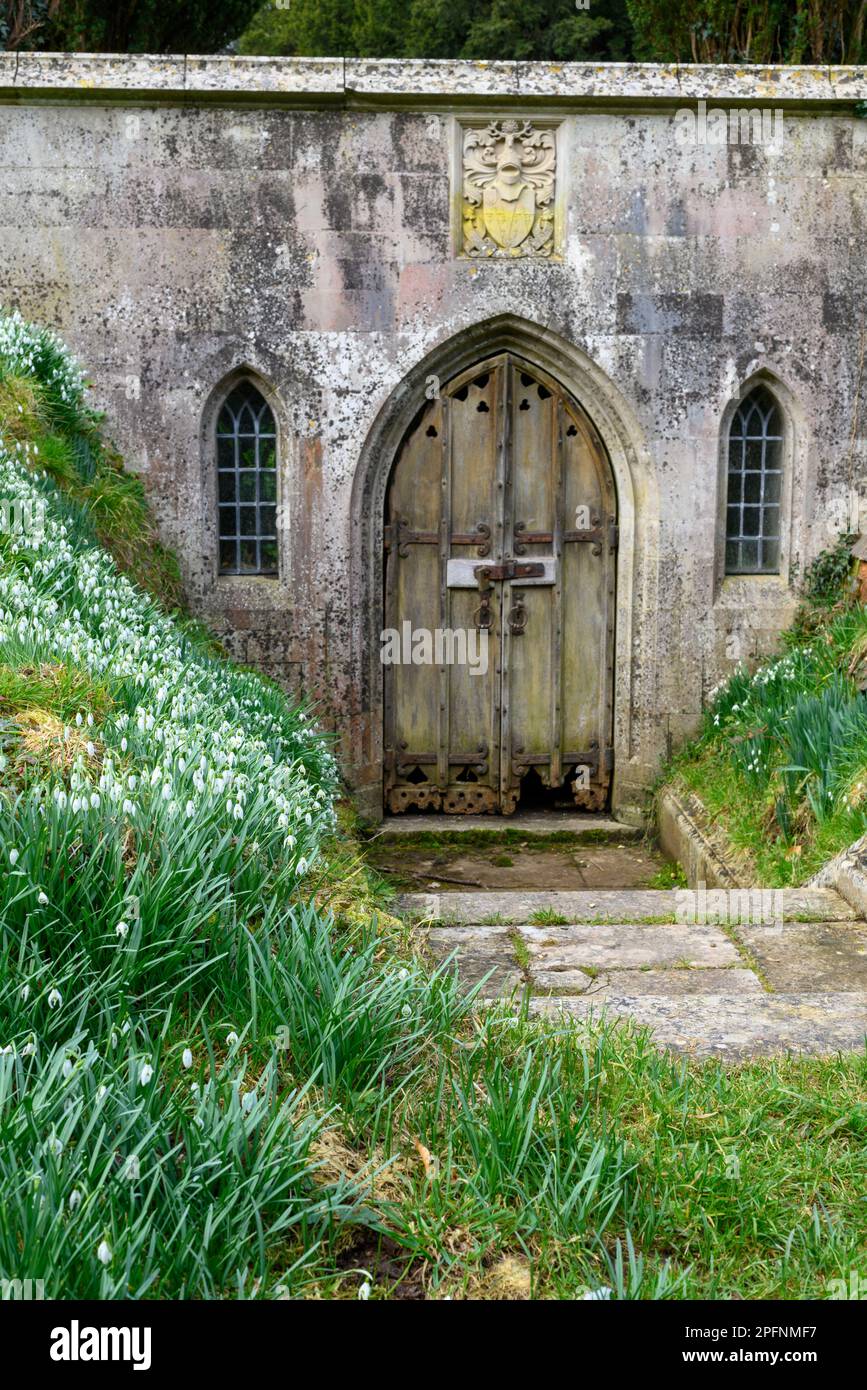 Entrata della cripta e vecchia porta di legno nei terreni della chiesa sassone di Santa Maria nel villaggio di Breamore, Fordingbridge, Hampshire, Inghilterra, Regno Unito Foto Stock