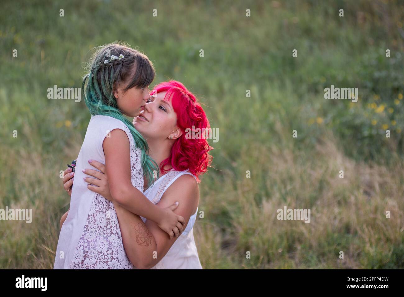 Luminosa, diversità, straordinaria madre e figlia che abbraccia la foresta. La donna ha i capelli rosa, la ragazza ha i capelli verdi. Tenera maternità, buon chi Foto Stock