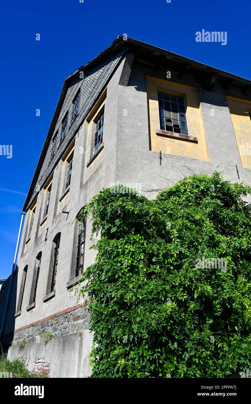 Facciata di una vecchia casa con finestre a griglia in metallo e vetri rotti in un vecchio edificio vacante Foto Stock