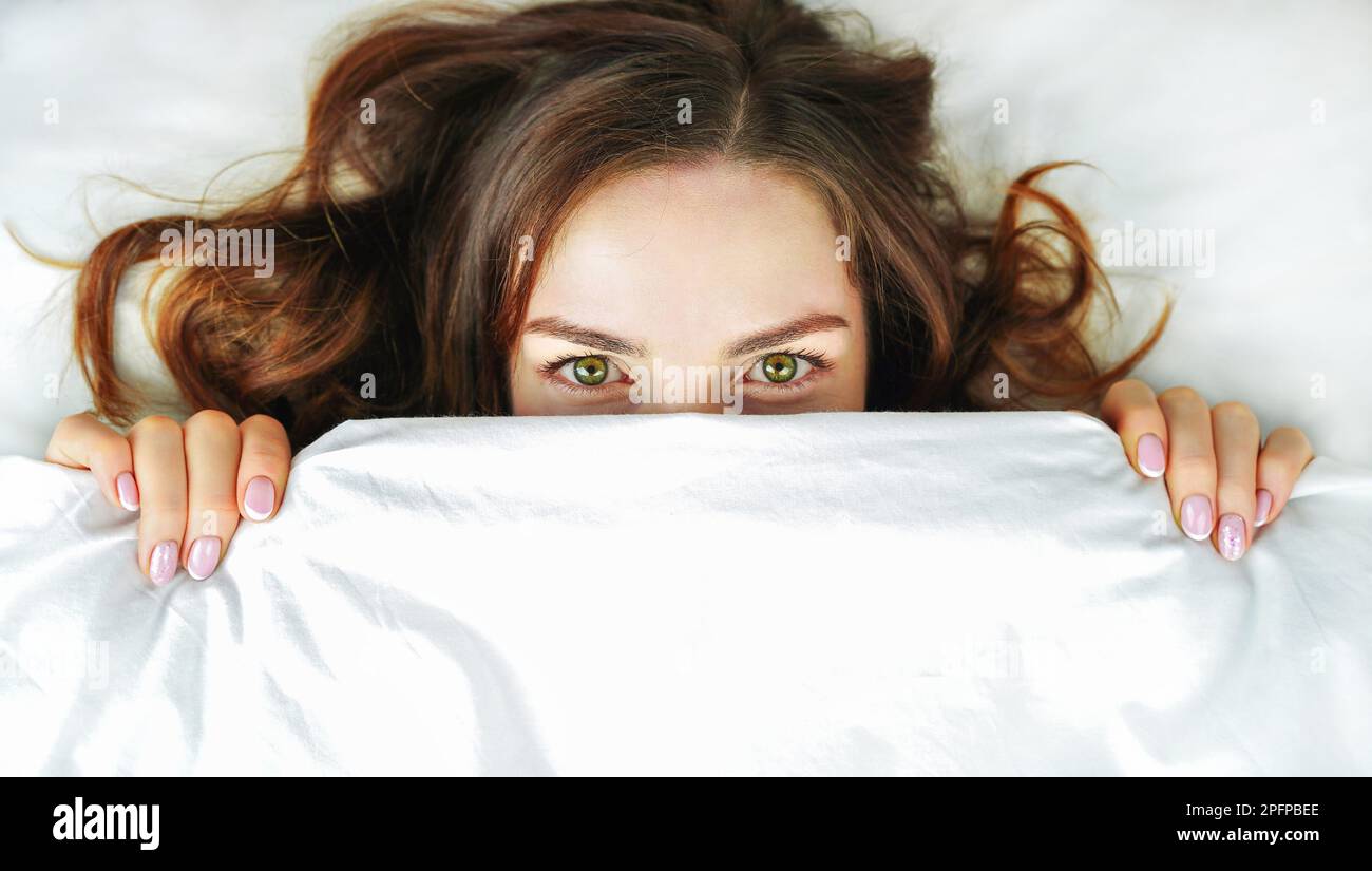 Donna a letto. Ragazza nasconde il suo volto sotto il covers.Concept di sonno sano, insonnia, zona di comfort Foto Stock