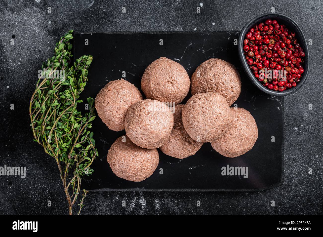 Polpette di vegano crude di carne vegetale con timo. Sfondo nero. Vista dall'alto. Foto Stock