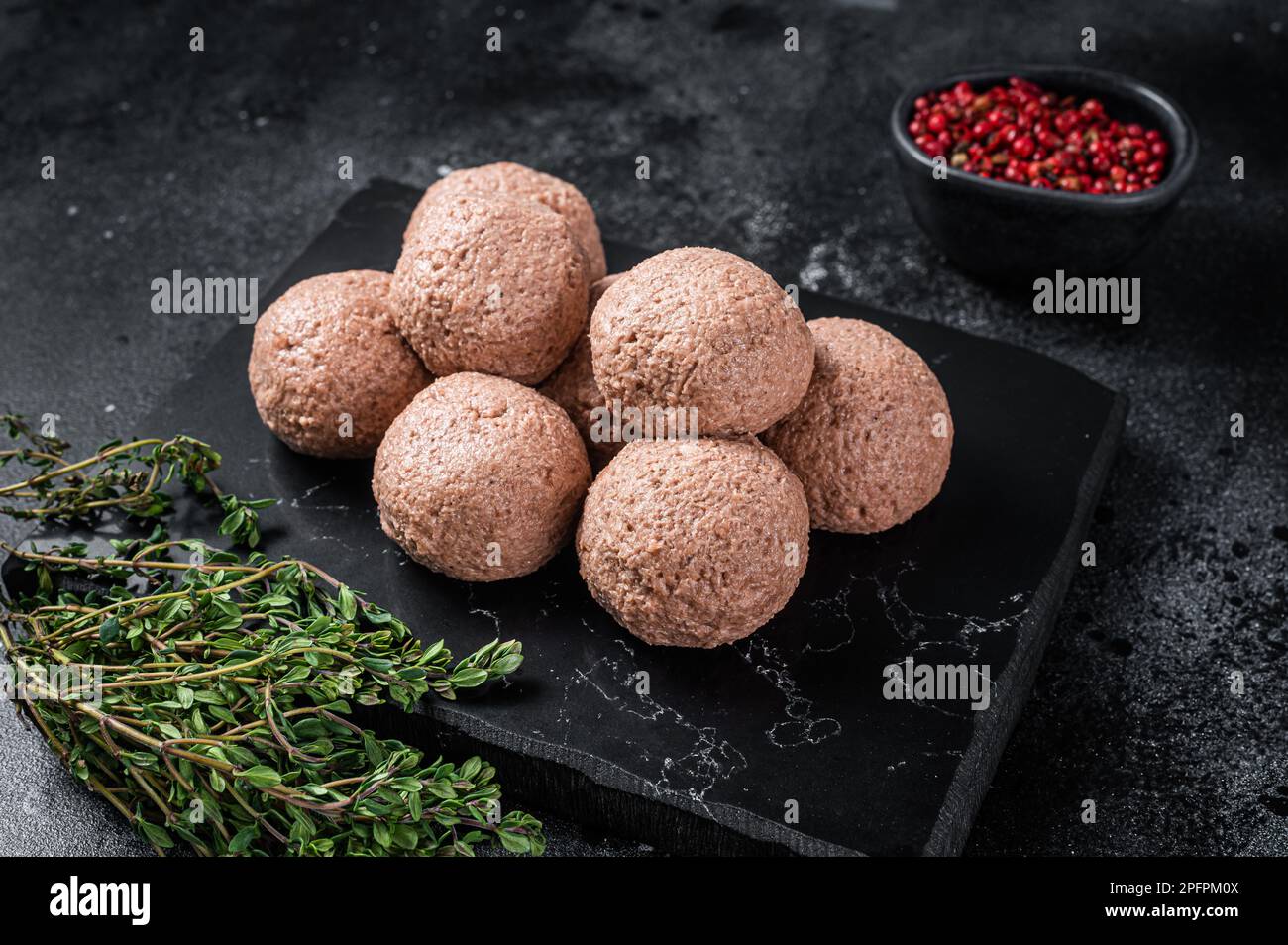 Polpette di vegano crude di carne vegetale con timo. Sfondo nero. Vista dall'alto. Foto Stock