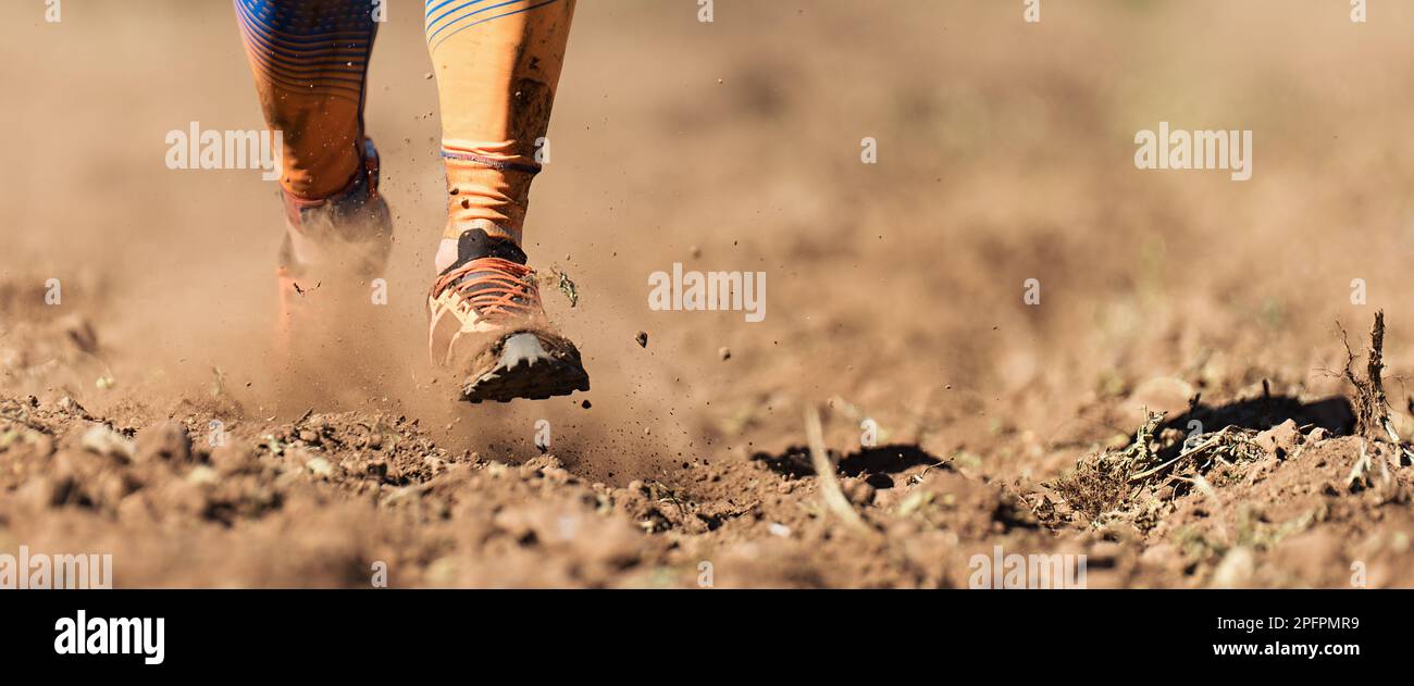 Atleta trail running che si esercita per il fitness e la salute all'aperto arato campo, primo piano di scarpe da running in azione Foto Stock