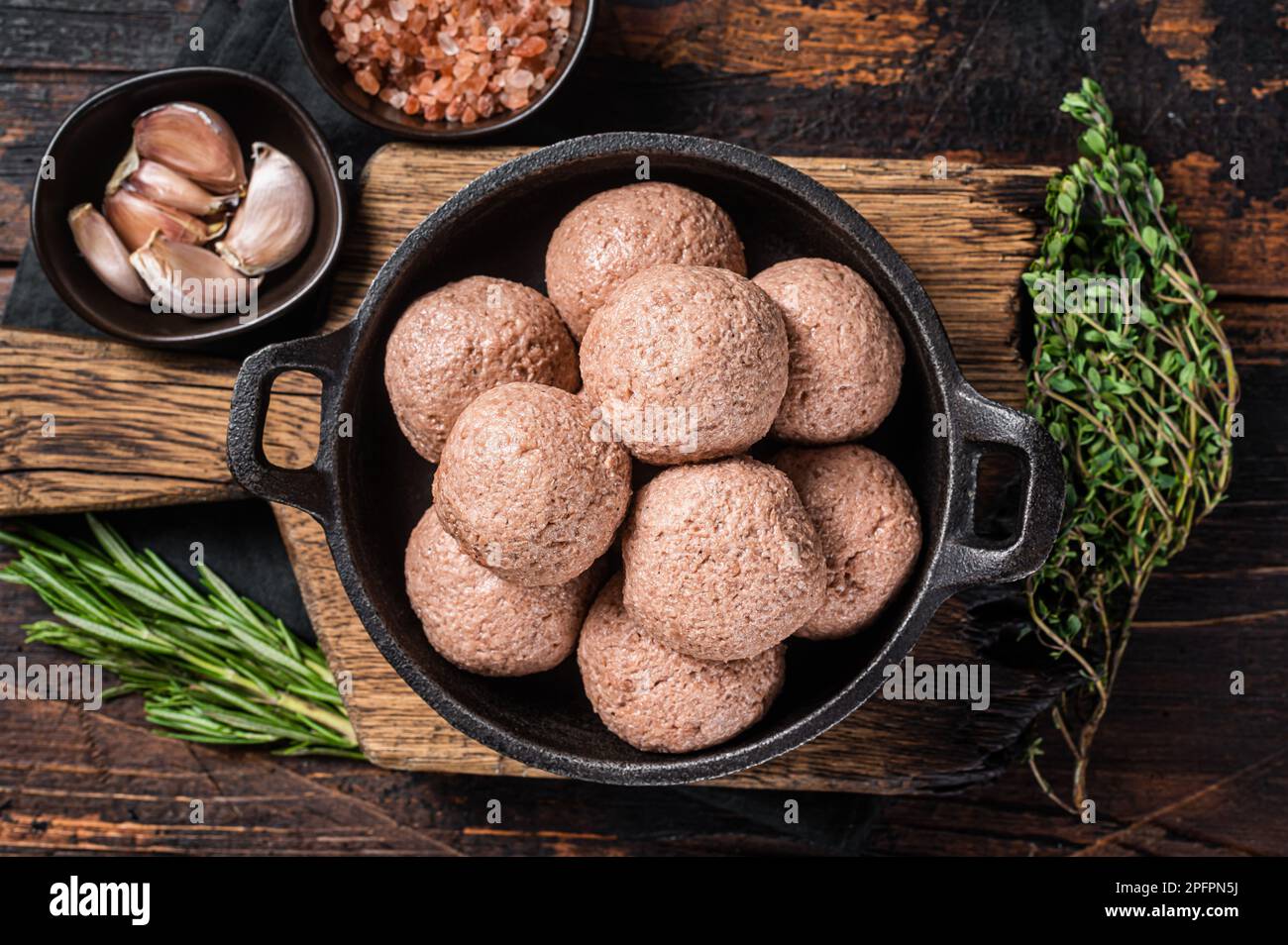 Polpette vegetariane senza carne di carne cruda a base di piante con timo e rosmarino. Sfondo di legno. Vista dall'alto. Foto Stock