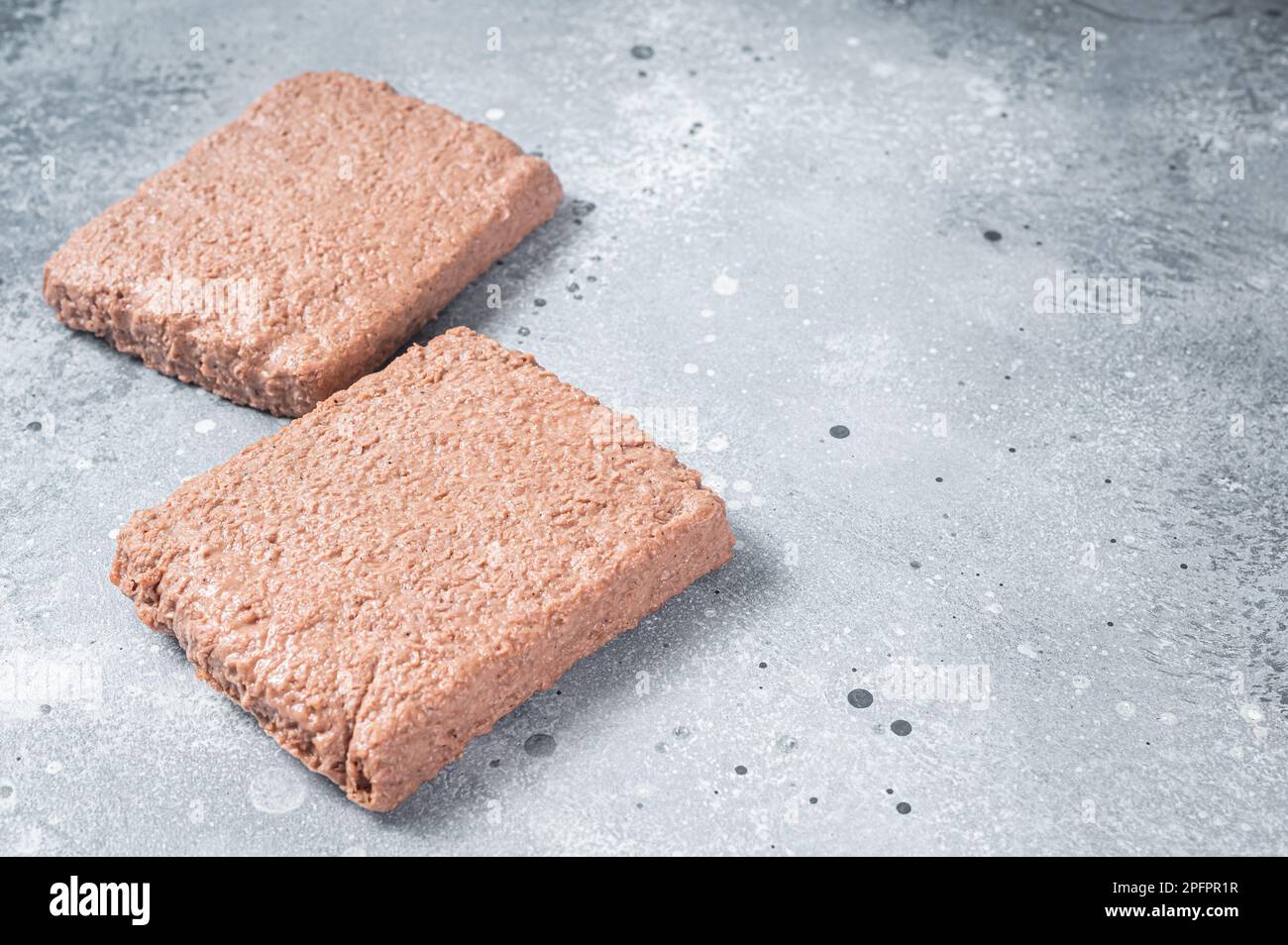 La carne a base di piante crude, gli alimenti riducono l'impronta di carbonio. Sfondo grigio. Vista dall'alto. Spazio di copia. Foto Stock