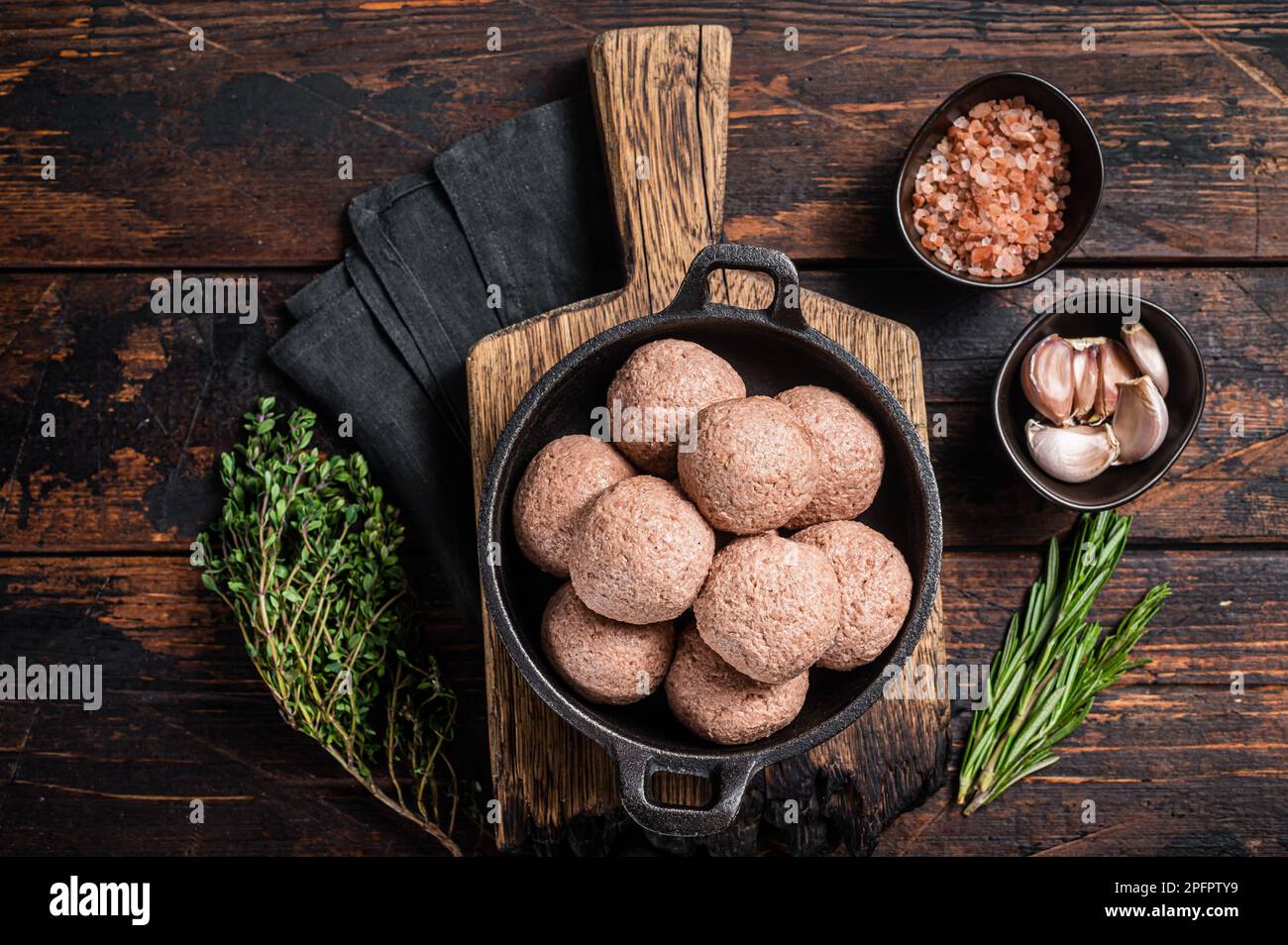 Polpette vegetariane senza carne di carne cruda a base di piante con timo e rosmarino. Sfondo di legno. Vista dall'alto. Foto Stock