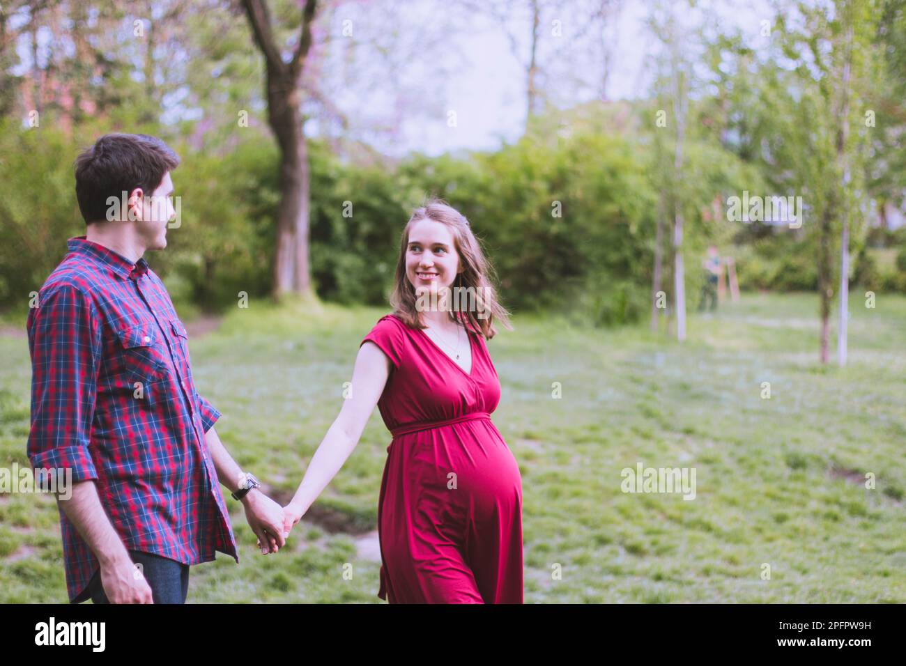 Giovane coppia sposata in attesa di un bambino presto, moglie in ultimo trimestre. Camminano nel parco. Foto Stock