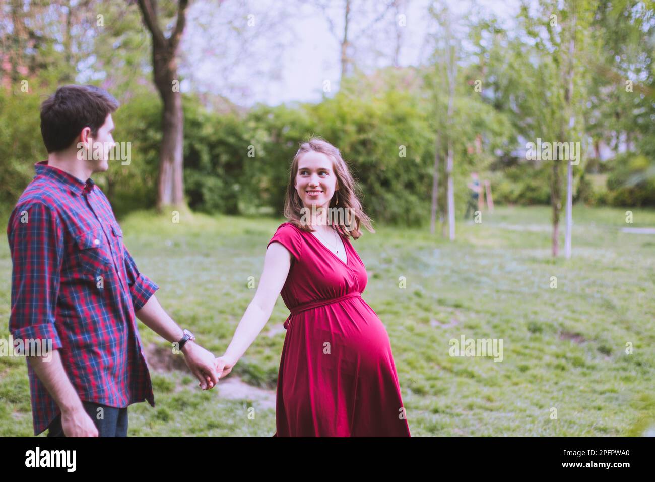 Giovane coppia sposata in attesa di un bambino presto, moglie in ultimo trimestre. Camminano nel parco. Foto Stock