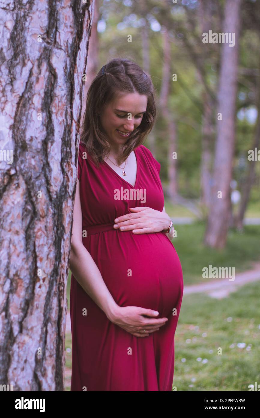 Giovane donna sposata in attesa di un bambino presto, è nell'ultimo trimestre. Lei è fuori nel parco. Foto Stock