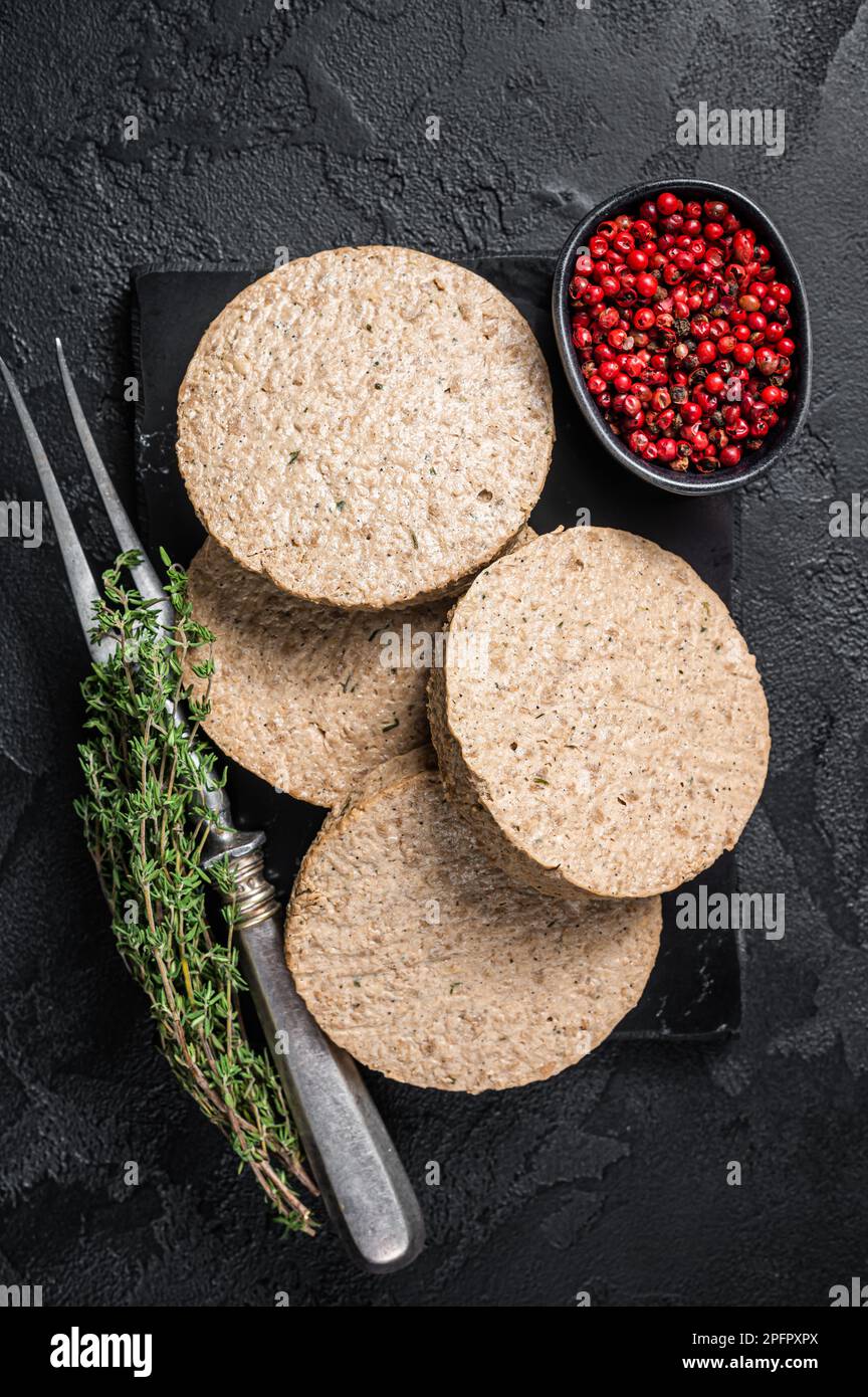 Hamburger crudi cotolette a base di carne vegetale, polpette di vegan crude. Sfondo nero. Vista dall'alto. Foto Stock