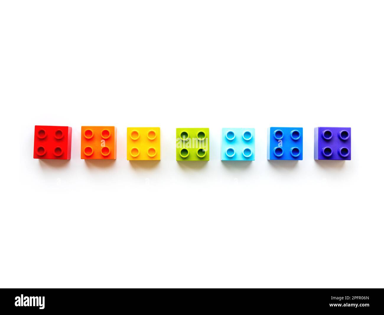 Set di blocchi costruttore colorati. Sette mattoncini giocattolo colorati arcobaleno che giacciono in ordine. Processo educativo - imparare i colori e i numeri con il bambino che usa Foto Stock