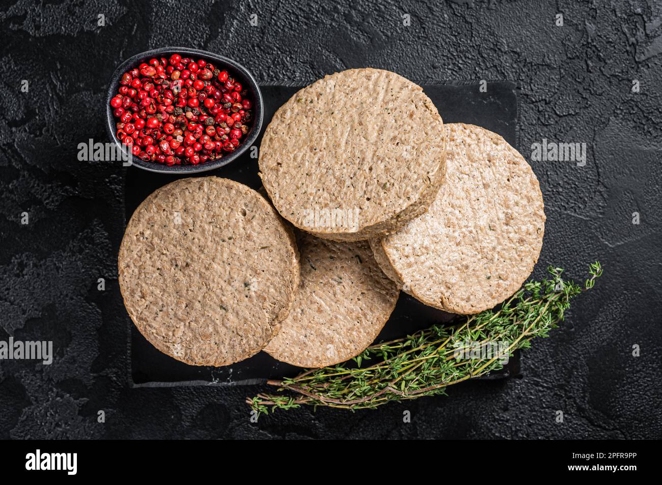 Hamburger crudi cotolette a base di carne vegetale, polpette di vegan crude. Sfondo nero. Vista dall'alto. Foto Stock