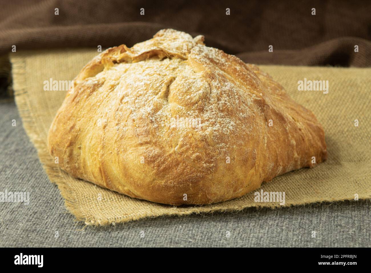 Una pagnotta di pane appena sfornato su un asciugamano. Pane fatto in casa delizioso e sano. Vista laterale Foto Stock