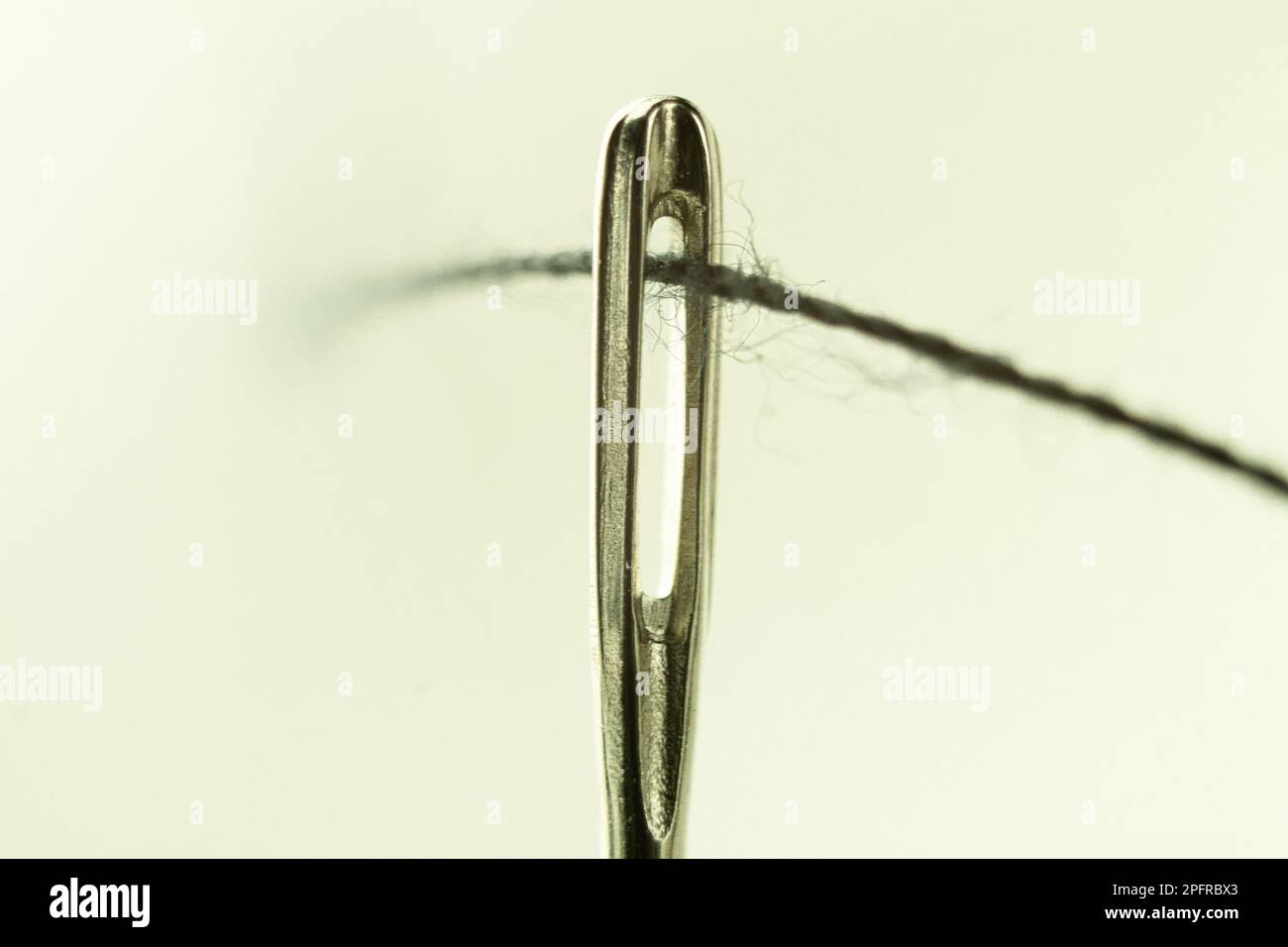 L'occhio di un ago con un filo vicino. Ago per cucire con filo penetrante. Utensile per cucire, ricamare Foto Stock