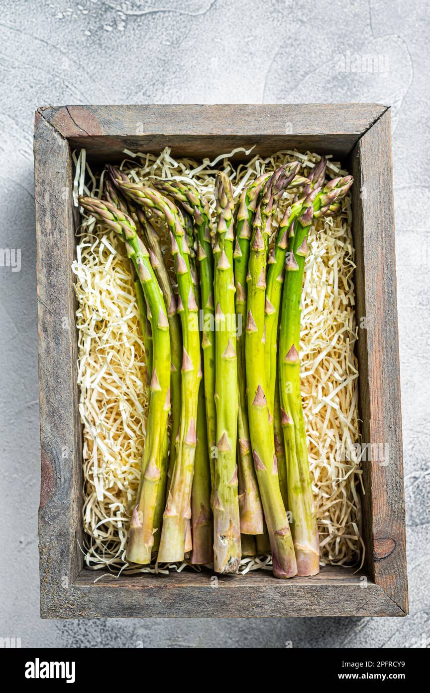 Asparagi verdi crudi in una scatola di legno. Sfondo bianco. Vista dall'alto. Foto Stock