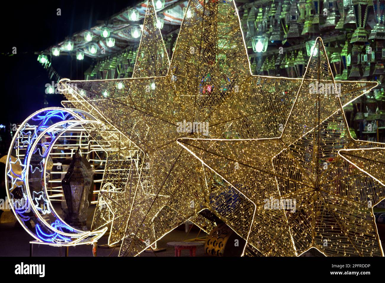 Sfondo delle decorazioni festive del mese del digiuno islamico del Ramadan nelle strade egiziane di notte con le luci LED delle stelle e dei simboli della luna crescente e. Foto Stock