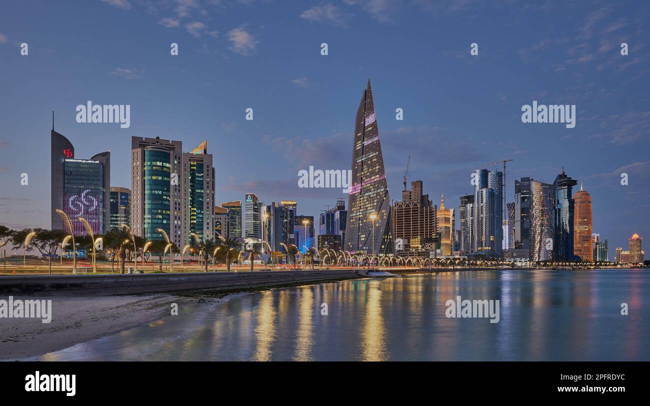 Lo skyline del Qatar di Doha dalla passeggiata sulla Corniche al crepuscolo mostra le luci dei grattacieli di West Bay che si riflettono nel golfo arabo Foto Stock