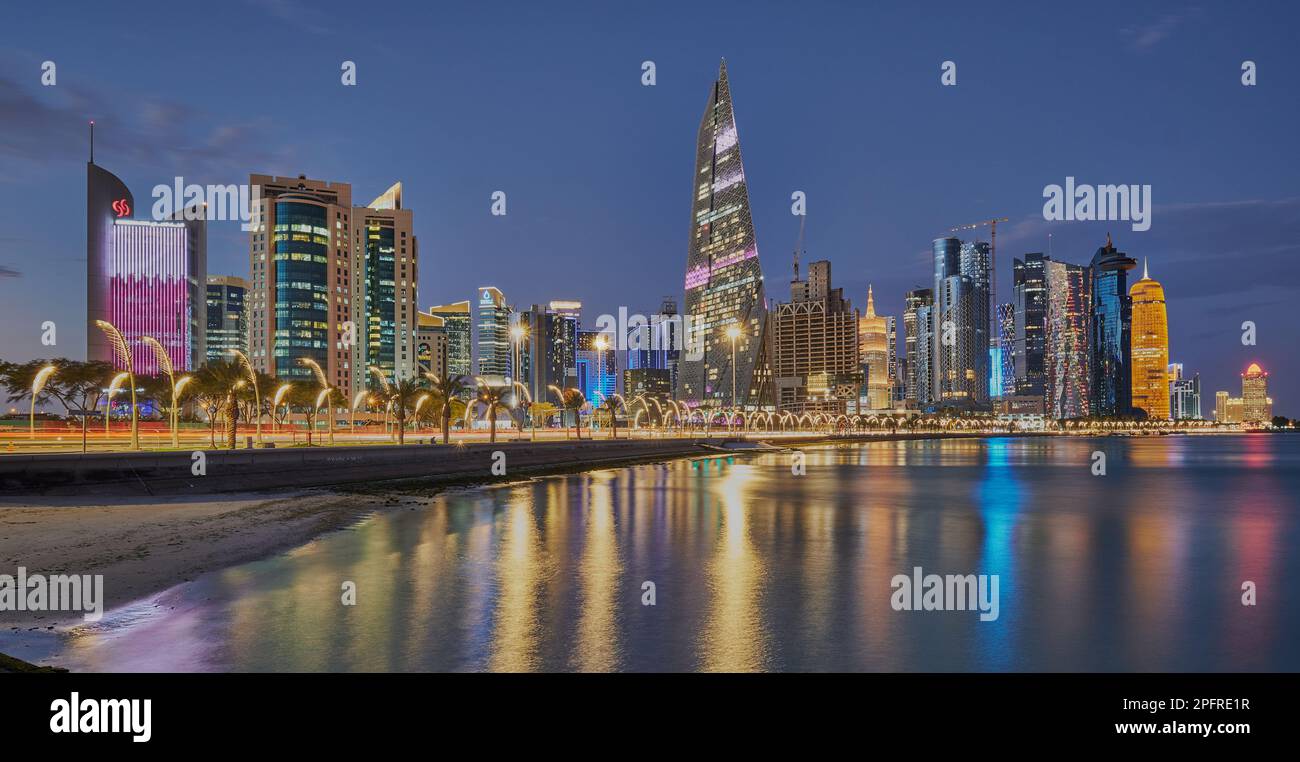 Lo skyline del Qatar di Doha dalla passeggiata sulla Corniche al crepuscolo mostra le luci dei grattacieli di West Bay che si riflettono nel golfo arabo Foto Stock