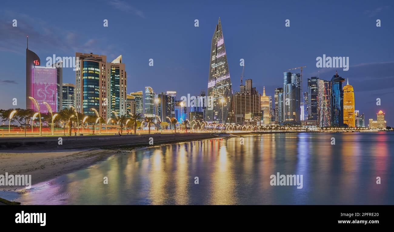 Lo skyline del Qatar di Doha dalla passeggiata sulla Corniche al crepuscolo mostra le luci dei grattacieli di West Bay che si riflettono nel golfo arabo Foto Stock