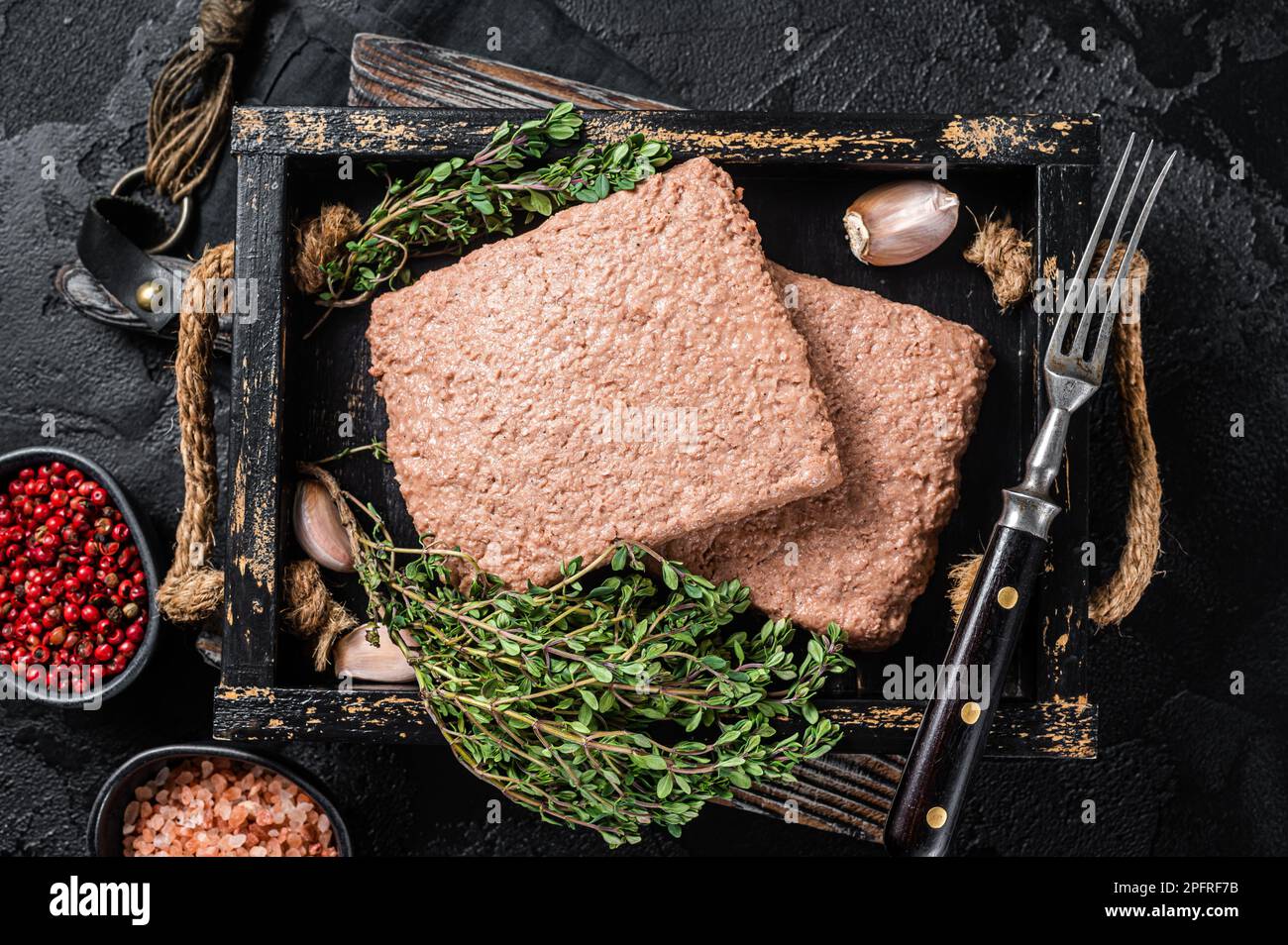 Carne vegana a base di piante crude con erbe aromatiche. Sfondo nero. Vista dall'alto. Foto Stock
