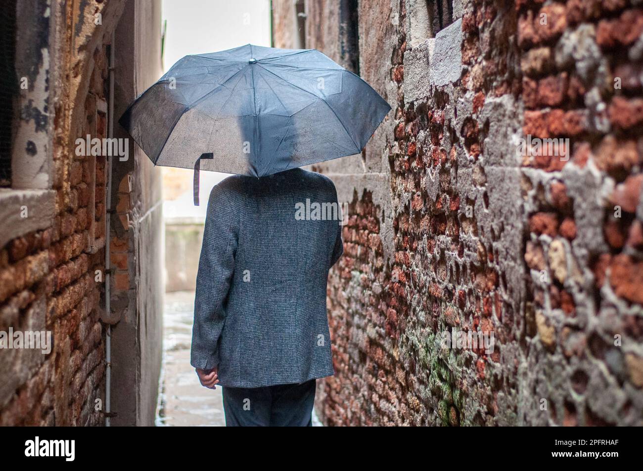 Vista posteriore dell'uomo che cammina sotto la pioggia. Foto Stock