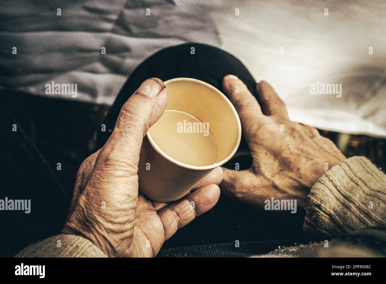 Dall'alto del raccolto anonimo uomo anziano indossando maglione seduto con tazza di carta beige di caffè Foto Stock