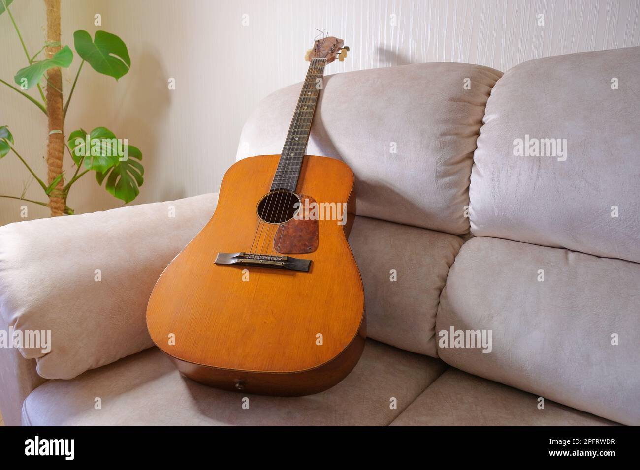 Vecchia chitarra acustica sdraiata sul divano del soggiorno Foto Stock