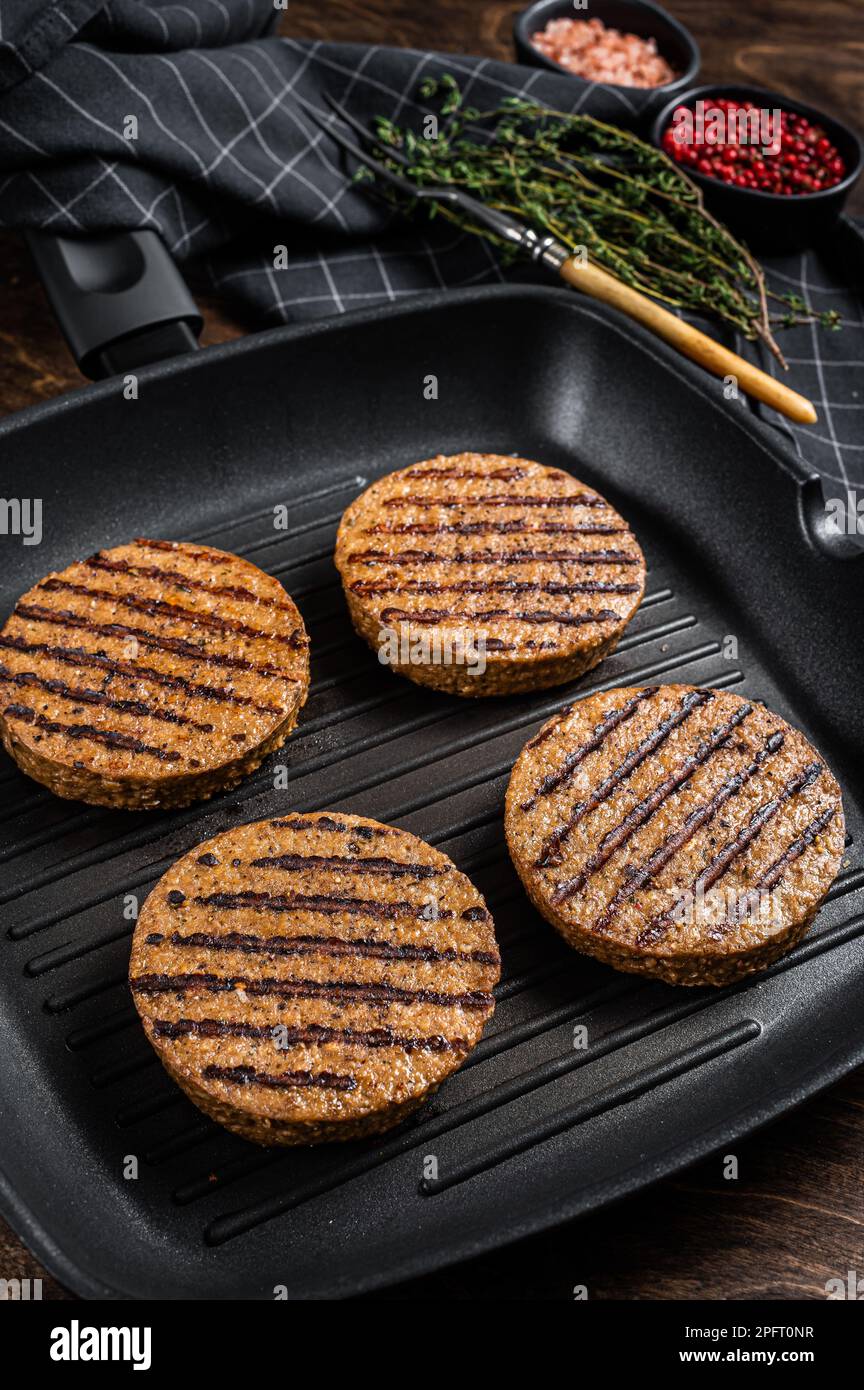 Hamburger di carne alla griglia a base di piante vegetali, cotolette vegane sulla padella alla griglia. Sfondo di legno. Vista dall'alto. Foto Stock