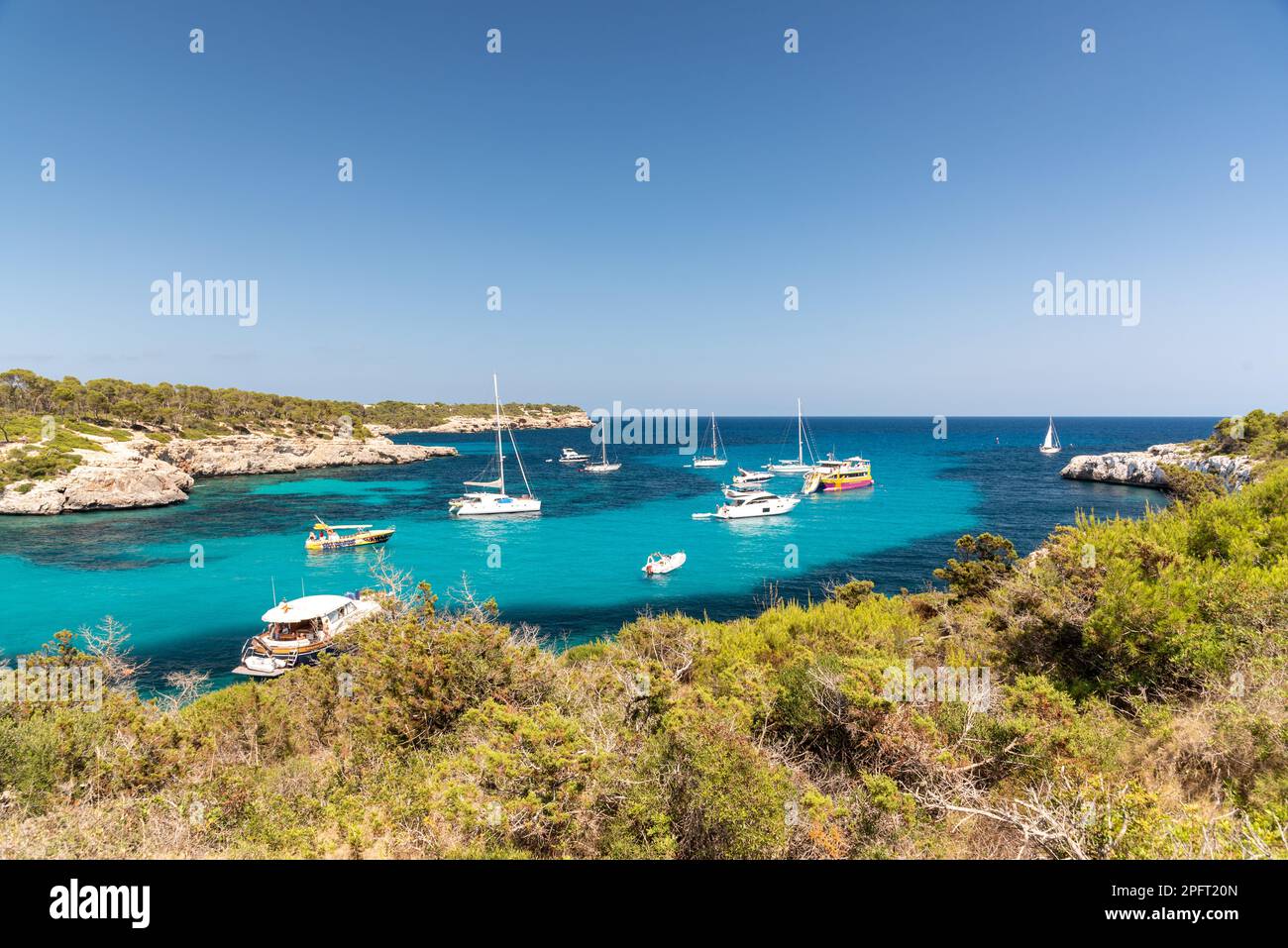 Le splendide acque turchesi e la soffice sabbia bianca della spiaggia di Cala Agulla a Maiorca, Spagna, attirano visitatori da tutto il mondo a crogiolarsi nella sua bellezza Foto Stock