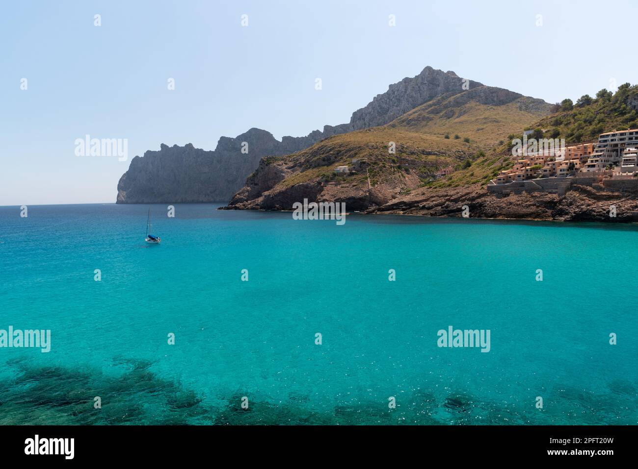 L''idilliaca Cala Santanyi di Maiorca, Spagna, vanta acque cristalline e una pittoresca spiaggia fiancheggiata da barche colorate, perfetta per nuotare e prendere il sole Foto Stock