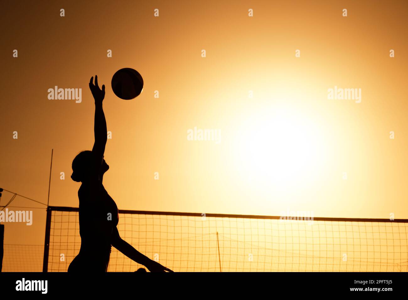 Silhouette donna che gioca a Beach volley al tramonto. Foto Stock