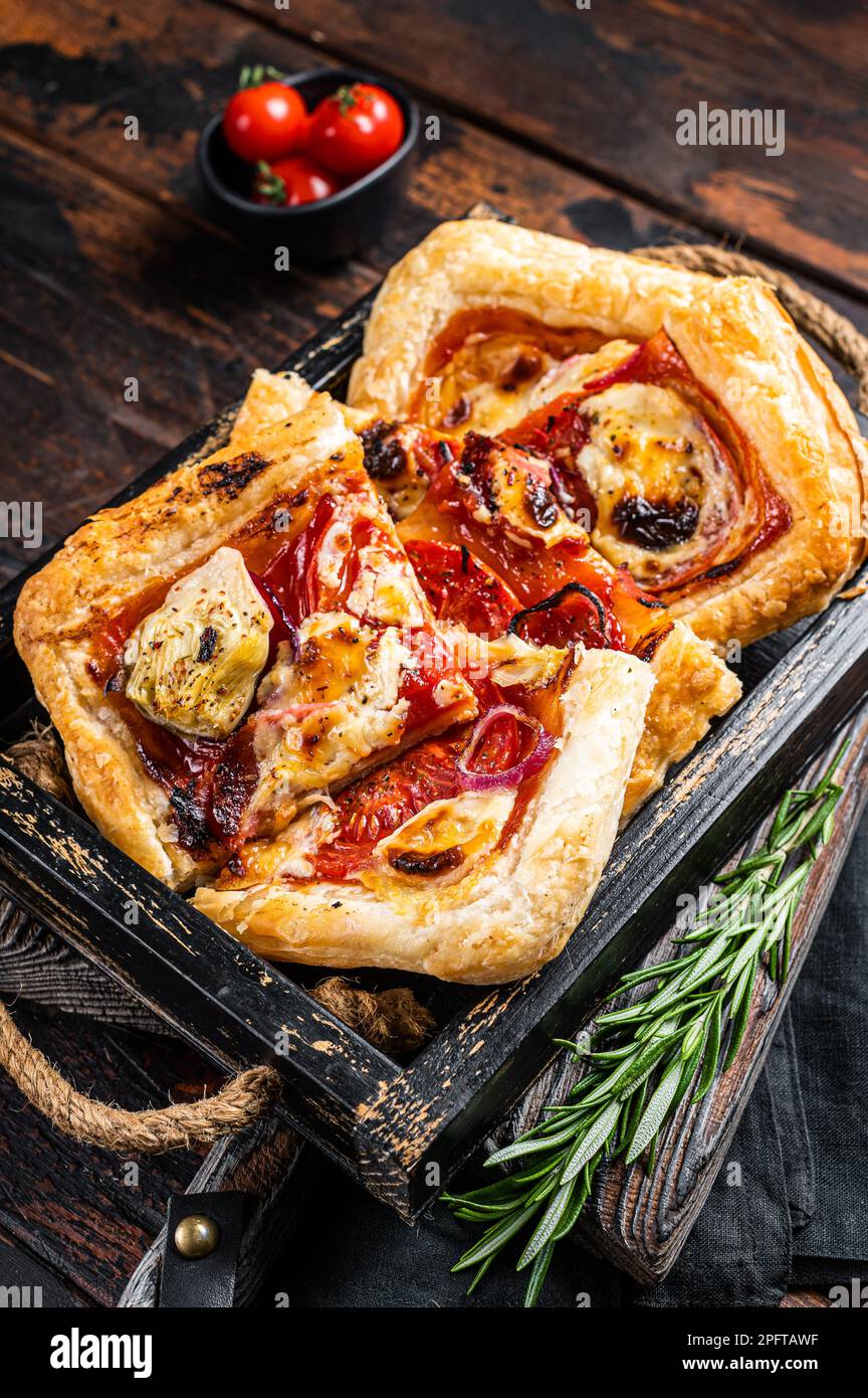 Pasta sfoglia crostata pizza con carciofo, mozzarella, pomodori e formaggio affettati in un vassoio di legno Sfondo di legno. Vista dall'alto. Foto Stock