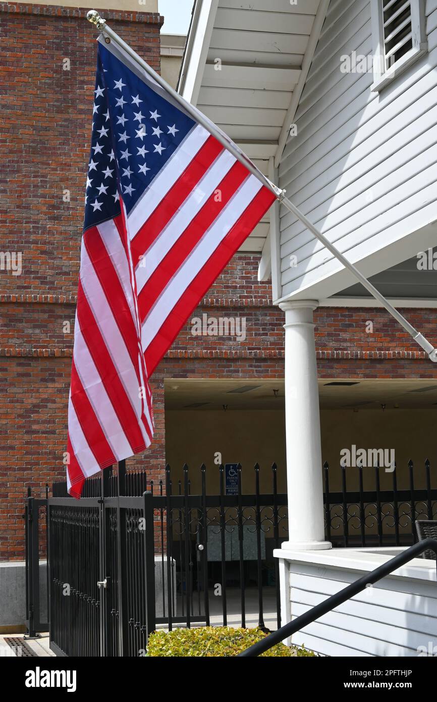 Primo piano di una bandiera americana sul portico anteriore di una vecchia casa di stile. Foto Stock