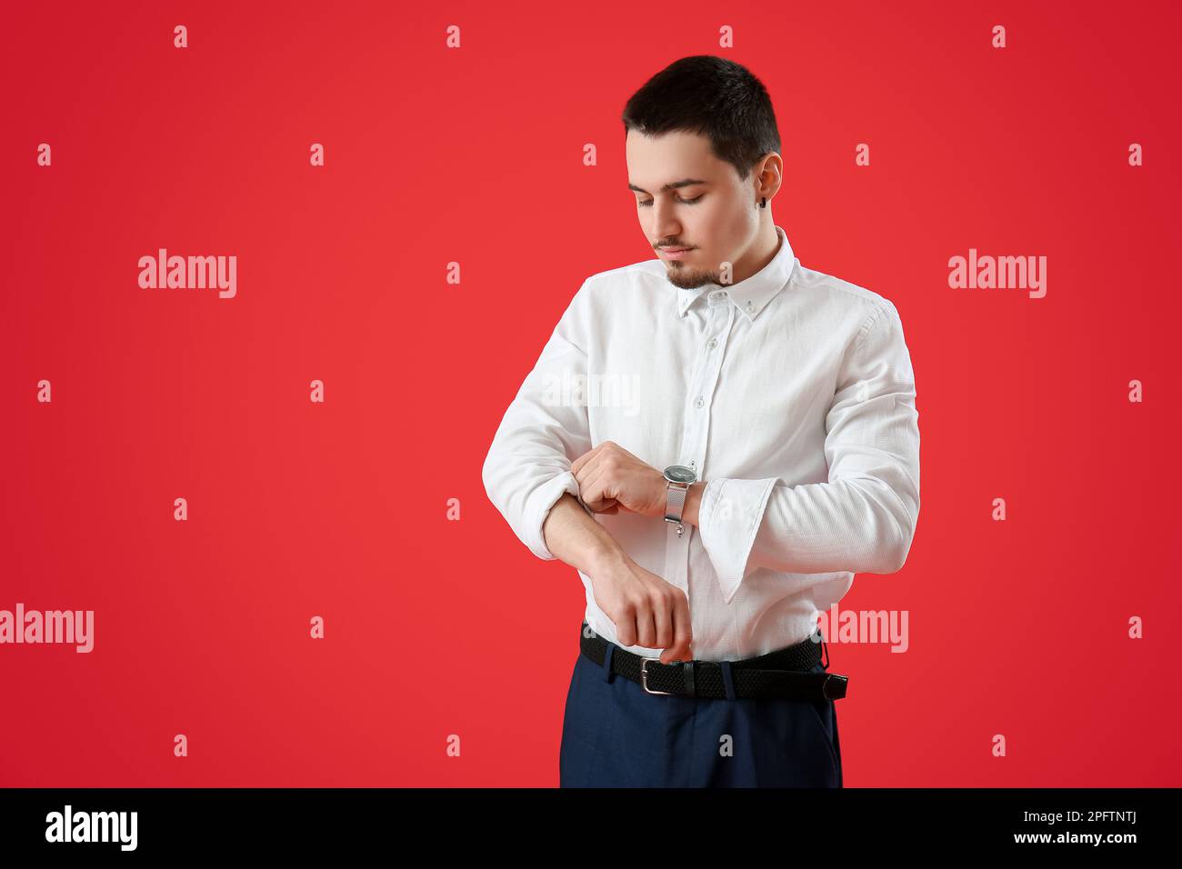 Giovane uomo d'affari che rotola la sua manica su sfondo rosso Foto Stock