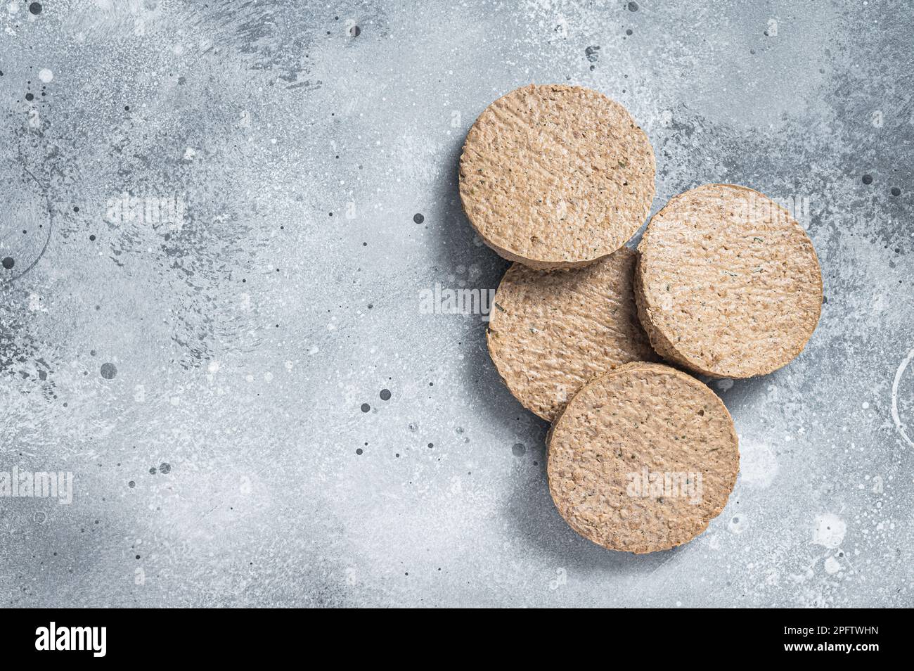 Carne cruda polpettine di hamburger a base di piante libere, cotolette vegetariane. Sfondo grigio. Vista dall'alto. Spazio di copia. Foto Stock
